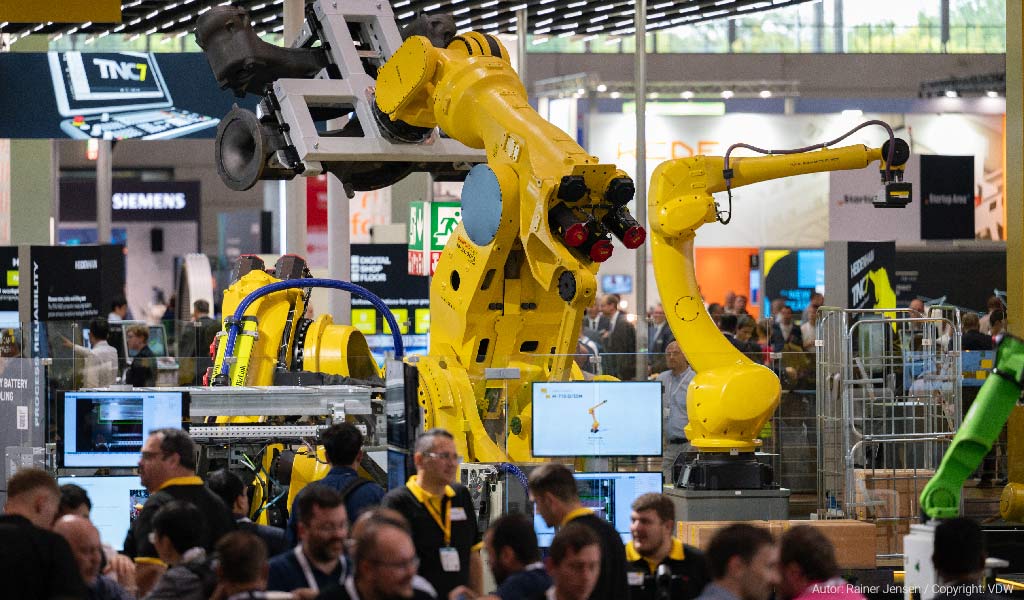 Visitantes de la EMO 2023 junto a robots colaborativos y maquinaria de FANUC.